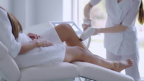 Depilacja laserowa. Kobieta poddawana laserowej depilacji na nogach. Beauty laser leczenie salon kosmetyka kosmetologia profesjonalny zawód pielęgnacja ciała koncepcja — Wideo stockowe