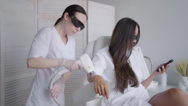 Procedure of removing hairs on hand. Laser hair removal on a diode laser, tracking moving camera. Woman cosmetologist applies laser hair removal gel on female hand. photoepilation, body care concept. — Stock Video