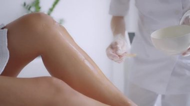 Use a stick to apply a moisturizing gel on the clients legs before laser hair removal on the legs. The doctor prepares his legs for laser hair removal in a beauty salon