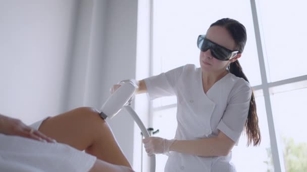 Laserepilatie en cosmetologie in schoonheidssalon. Cosmetologie, spa en ontharing concept. Laserontharing van vrouwelijke benen. arts in handschoenen. — Stockvideo