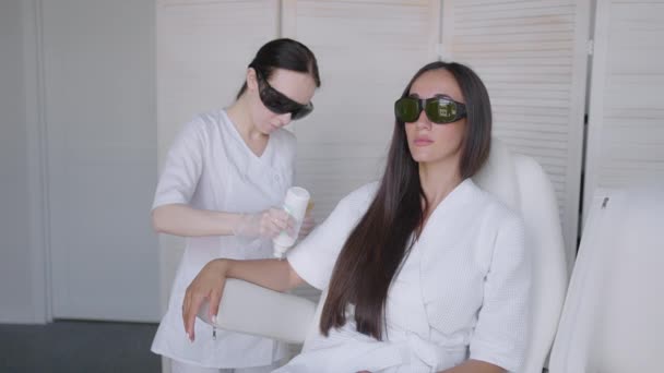 Procedure of removing hairs on hand. Laser hair removal on a diode laser, tracking moving camera. Woman cosmetologist applies laser hair removal gel on female hand. photoepilation, body care concept. — Stock video