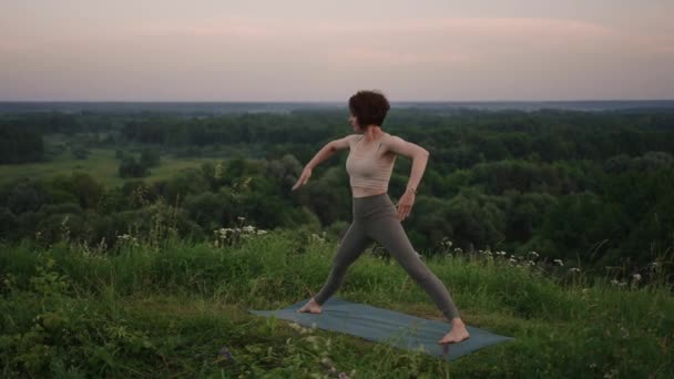 Linda chica haciendo yoga y pilates en el bosque de montaña. Chica fitness entrenamiento al aire libre en el paisaje de la naturaleza. — Vídeo de stock