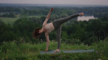 Bir yoga ustası denge ve esneme egzersizleri yapar. Ormandaki dağlarda yoga yapan bir kızın huzur ve rahatlığı.