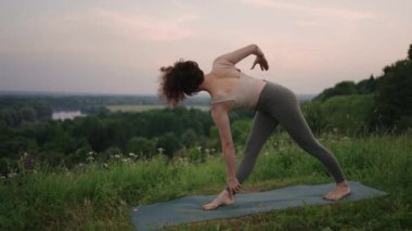 Kadın gün doğumunda çam ormanında yoga yapıyor. Genç ruhani kızın silueti Lotus 'ta meditasyon yapıyor, doğaya poz veriyor, ağır çekimde. Zindelik kavramı, sağlıklı yaşam tarzı