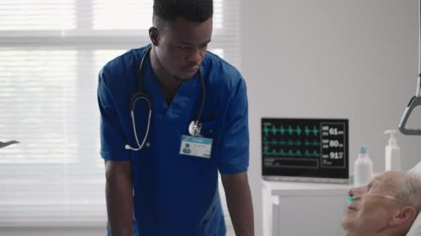 Starší pacient na lůžku mluví se 2 afroamerickými lékaři v nemocničním pokoji, Zdravotní péče a pojetí pojištění. Lékař uklidňující starší pacient v nemocniční posteli nebo radu diagnózy zdraví. — Stock video