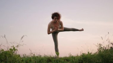 Bir yoga ustası denge ve esneme egzersizleri yapar. Ormandaki dağlarda yoga yapan bir kızın huzur ve rahatlığı.