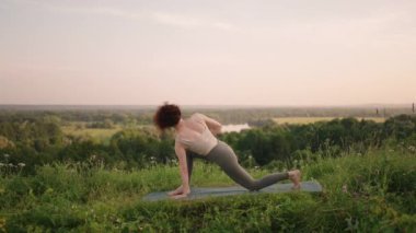 Yoga ustası denge ve ruh gelişimi için çeşitli egzersizler ve hareketler yapar. Sabahın erken saatlerinde ormanın dağlarında ağır çekimde ayakta durur.