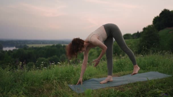 A jóga mester különböző gyakorlatokat és mozdulatokat végez az egyensúly és a lélek fejlődése érdekében, miközben kora reggel az erdőkben áll lassított felvételen. — Stock videók