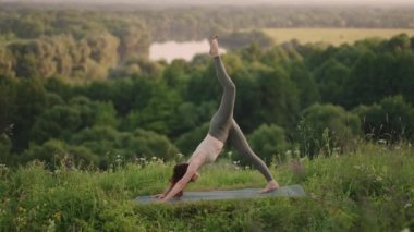 Dağ ormanında yoga ve pilates yapan güzel bir kız. Fitness kızı doğa manzarasında eğitim görüyor..