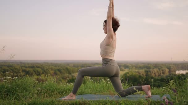 Bir yoga ustası denge ve esneme egzersizleri yapar. Ormandaki dağlarda yoga yapan bir kızın huzur ve rahatlığı. — Stok video