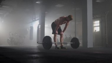 Spor salonundaki yoğun egzersizden sonra yorgun gençler dinleniyor. Spor salonundaki antrenmandan sonra yorgun ve sağlıklı bir adam. Yorgun erkek model, yoğun egzersizden sonra ayakta duruyor ve dinleniyor..