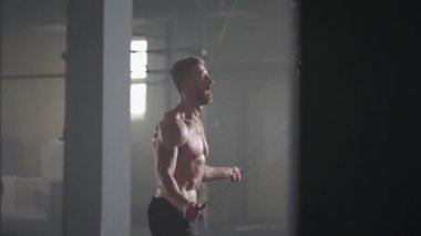 İp atlayan genç bir erkek atletin portresi. Yavaş çekim erkek sporcu spor salonunda ip atlama egzersizi yapıyor..