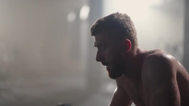 Jóvenes agotados descansando después de un entrenamiento intensivo en el gimnasio. Fitness hombre sano cansado después del ejercicio de entrenamiento de fuerza en el gimnasio. Modelo de ajuste masculino cansado con pie y relajante después de un entrenamiento intenso. — Vídeo de stock