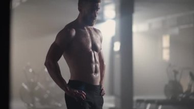 Spor salonundaki yoğun egzersizden sonra yorgun gençler dinleniyor. Spor salonundaki antrenmandan sonra yorgun ve sağlıklı bir adam. Yorgun erkek model, yoğun egzersizden sonra ayakta duruyor ve dinleniyor..