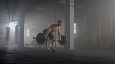 Ağır çekimde: Zalim sporcu çıtayı kendi üzerine kaldırır, bir pislik gibi davranır, dönen bir itiş. Bir adam karanlık bir arkaplanda halter kaldırmakla meşgul. Portre. Güç kavramı, güç, spor yapmak..