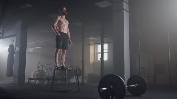 Slow motion: Muscular Shirtless Fit Man Energetically Box Jumps in Hardcore Gym doing Part of His Cross Fitness Training Plan. El hombre es sudoroso de entrenamiento intenso — Vídeo de stock