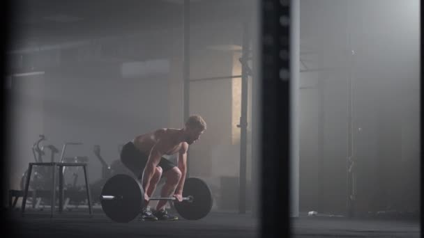 Zpomalený pohyb crossfit sportovec provádí čistě a trhaně. Mladý muž dělá čisté a blbec vzpírání cvičení v tělocvičně. — Stock video