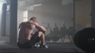 Spor salonundaki yoğun egzersizden sonra yorgun gençler dinleniyor. Spor salonundaki antrenmandan sonra yorgun ve sağlıklı bir adam. Yorgun erkek model, yoğun egzersizden sonra ayakta duruyor ve dinleniyor..