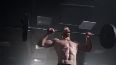 Crossfit atlet yavaş hareket ediyor ve temiz ve pislik yapıyor. Spor salonunda halter kaldırma egzersizi yapan genç adam..