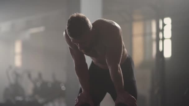 Utmattade unga män vilar efter intensiv träning i gym. Fitness frisk man trött efter styrketräning motion på gym. Trött hane passform modell med stående och avkopplande efter intensiv träning. — Stockvideo