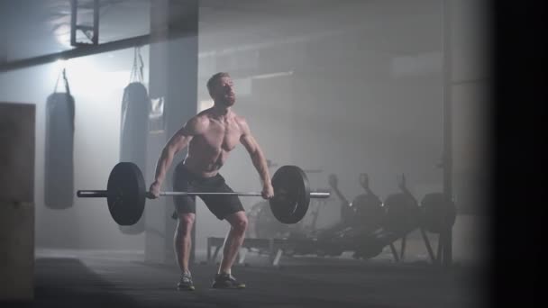 Movimiento lento: El atleta brutal levanta la barra por encima de sí mismo, realizando un tirón, un empujón giratorio. Un hombre se dedica a levantar pesas sobre un fondo oscuro, retrato. Concepto fuerza, poder, practicar deportes. — Vídeo de stock