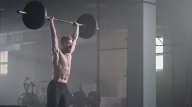 Crossfit atlet yavaş hareket ediyor ve temiz ve pislik yapıyor. Spor salonunda halter kaldırma egzersizi yapan genç adam..