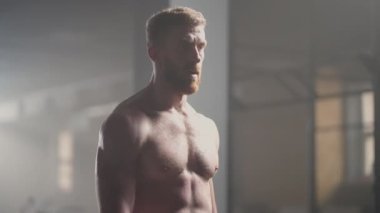 Güzel atletik adam alnından terini eliyle siliyor ve kameraya bakıyor. Yoğun Çapraz Vücut Egzersizinden Yorgun