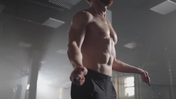 Een jonge atleet met prominente spieren springt in slow motion op een touw in de sportschool — Stockvideo