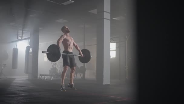 A young male weightlifter lifts a heavy barbell over his head performing a jerk. the jerk of a heavy barbell in slow motion — Stock Video