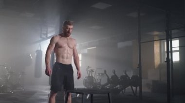 Sporcu egzersiz yaptı. Kutunun üstüne atlamak. Küp 'e atlayan güçlü bir erkek atlet. Spor salonundaki yoğun idman sırasında formda bir sporcunun kübün üzerine atlaması.