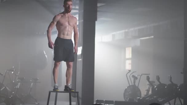 El atleta hizo ejercicio. Saltando sobre la caja. Fuerte atleta masculino saltando en primer plano del cubo. Tracking shot de la deportista en forma saltando en el cubo durante el entrenamiento intenso crossfit en el gimnasio — Vídeos de Stock