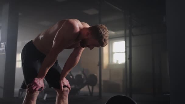 Hermoso hombre atlético limpia el sudor de su frente con una mano, mira a la cámara. Se cansó después del ejercicio intensivo de Cross Fitness — Vídeo de stock