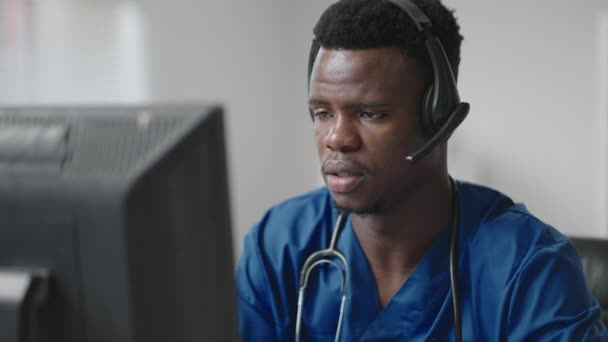 Médico o enfermera afroamericana con auriculares y computadora trabajando en el hospital .young terapeuta profesional médico consultando cliente cliente utilizando la comunicación remota hablando por webcam — Vídeos de Stock