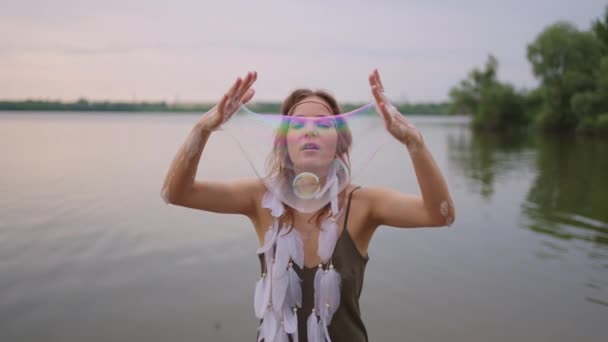 A young female artist shows a soap bubble show by blowing up large soap bubbles with her hands in slow motion — Stock Video