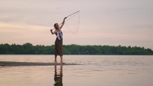 Uma jovem artista mostra truques mágicos usando enormes bolhas de sabão. Criar bolhas de sabão usando paus e corda ao pôr do sol para mostrar um show de circo teatral — Vídeo de Stock