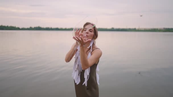 A young female artist shows a soap bubble show by blowing up large soap bubbles with her hands in slow motion — Stock Video