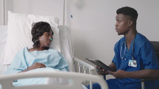 Młody afro-amerykański lekarz rozmawia z pacjentem. Czarna kobieta rozmawia z lekarzem. — Wideo stockowe