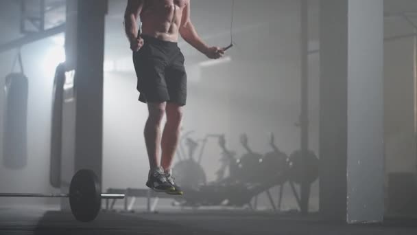 Hombre joven haciendo ejercicio usando la cuerda de saltar en el gimnasio. Hombre atlético entrenando duro en el gimnasio. — Vídeos de Stock