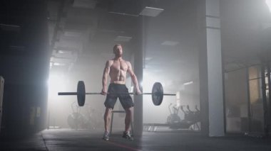 Ağır çekim: Adam spor salonunda kaldırma egzersizi yapıyor.