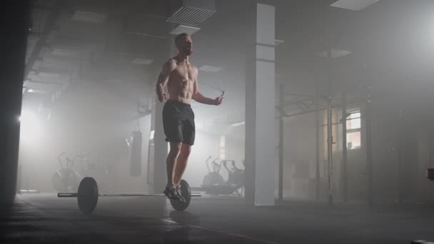 Mladý muž cvičí pomocí švihadla v tělocvičně. Atletický muž tvrdě trénuje v tělocvičně. — Stock video