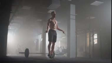 Genç adam spor salonunda ip atlama egzersizi yapıyor. Sporcu adam spor salonunda sıkı çalışıyor..