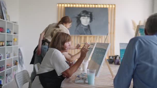 Como amigos mayores que asisten juntos a una clase de pintura. grupo pequeño tomando una variedad de clases divertidas juntos. Un grupo de personas mayores asiste a una clase magistral sobre dibujar juntos pasar tiempo. — Vídeos de Stock