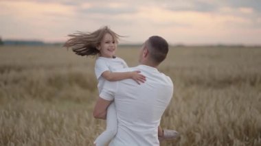 Bir baba gün batımında sevgili kızına sarılır ve etrafında döner. Gün batımında bir kızın tarlasında ağır çekim dönüyor.