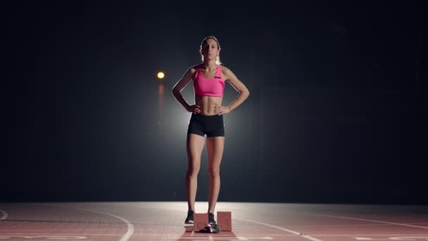 Atletas do sexo feminino se aquecendo na pista de corrida antes de uma corrida. Em câmara lenta. Mulher corredor no atletismo pista agachado nos blocos iniciais antes de uma corrida. — Vídeo de Stock