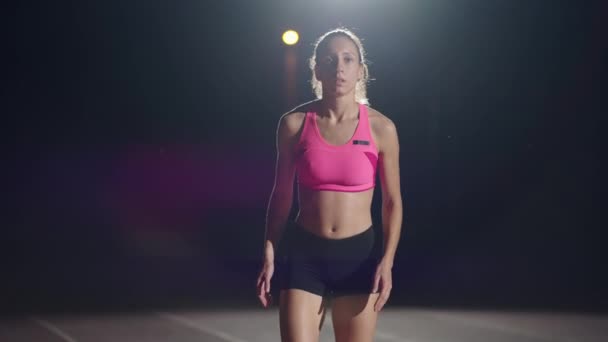 Mujer de cámara lenta preparándose para la carrera en la carrera de atletismo. Concentración y calentamiento antes de la competencia. Estabilidad psicológica y tenacidad de una atleta — Vídeos de Stock