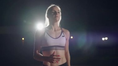 Ağır çekimde koşan kadın yarış için hazırlanıyor. Yarışmadan önce konsantrasyon ve ısınma. Psikolojik istikrar ve bir kadın sporcunun azmi