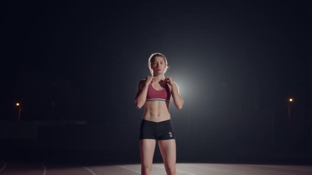 Una joven está sola en el estadio de atletismo y se prepara para la carrera. Preparación para el sprint. Concentración y preparación psicológica para competiciones en cámara lenta — Vídeo de stock