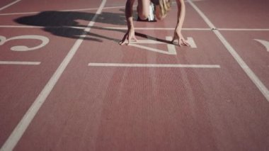 Koşu parkurunda koşmaya başlayan bir bayan sporcunun ön görüntüsü. Koşucu koşu parkurundan kalkıyor. Kamerayı yakınlaştır. Yavaş çekim