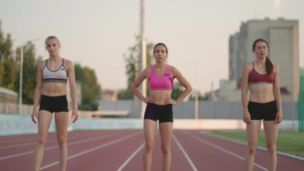 Yarış pistindeki bir grup kadın ısınıp yarışa hazırlanıyor. Stadyumdaki başlangıç çizgisine odaklan. — Stok video
