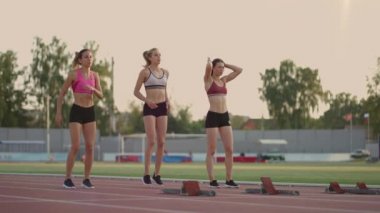 Üç bayan sporcu aynı anda maraton, rekabet ve ağır çekimde koşmaya başlıyor. Kadınlar yarıştan önce başlangıç çizgisinde duruyorlar.